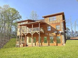 a large wooden house on top of a lush green field at Majestic Springs Lodge Cabin in McCookville