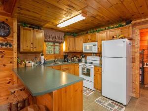 a kitchen with a white refrigerator and wooden cabinets at Forest Fling Cabin in McCookville