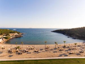 a beach with chairs and palm trees and the ocean at Six Senses Kaplankaya in Akbük