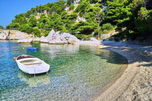 a white boat in the water next to a beach at Apartments & Restaurant Galeb in Marusici 