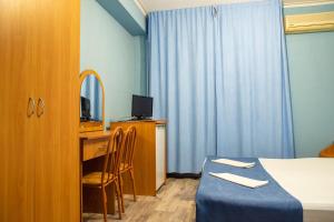 アナパにあるHotel Kosmosのベッド、鏡付きのデスクが備わるホテルルームです。