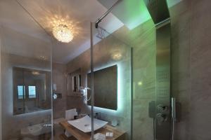 a bathroom with a sink and a glass shower at Artemide Hotel in San Vito lo Capo