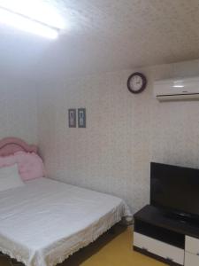 a bedroom with a bed and a clock on the wall at Dasanbang Pension in Yangyang