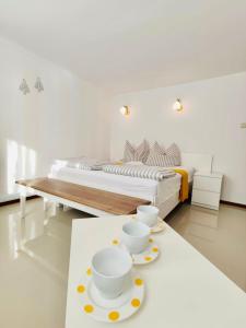 a white room with a bed and two cups on a table at IWONA Pokoje Apartamenty in Karwia