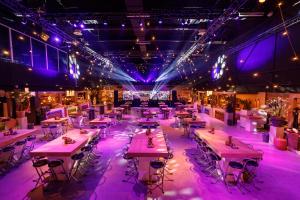 - un groupe de tables dans une pièce à éclairage violet dans l'établissement Fletcher Hotel-Restaurant Wings-Rotterdam, à Rotterdam