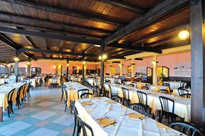 un comedor con mesas y sillas blancas en Le Tonnare di Stintino - Beach Resort en Stintino