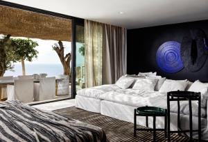 Myconian Panoptis Escape, a member of Small Luxury Hotels of the World في شاطئ إليا: غرفة نوم بسرير ونافذة كبيرة