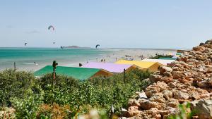 a beach with people in the water and people flying kites at PK25 Dakhla in Dakhla