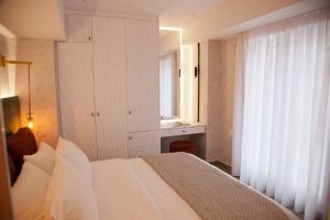 a bedroom with a white bed and a white dresser at Noufara in Piraeus