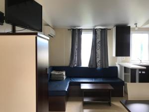 a living room with a blue couch in front of a window at Camping Castell D'aro in Platja d'Aro