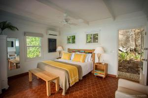 a bedroom with a bed with yellow pillows and a table at Dream Villa St-Jean 597 in Saint Barthelemy