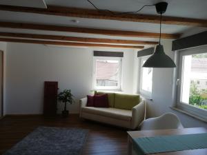 a living room with a couch and two windows at fewoflagmeier Meidelstetten I Maisonetten Wohnung Alb in Hohenstein