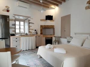 a white bedroom with a large bed and a kitchen at En Patmo Holiday Home in Patmos