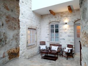 a patio with chairs and a table in a stone wall at En Patmo Holiday Home in Patmos