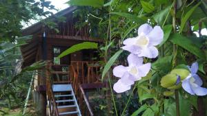 a tree house in the jungle with purple and white flowers at Shan Home Stay Sigiriya in Sigiriya