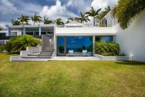 una gran casa blanca con 2 sillas en el césped en Dream Villa Lurin 829, en Gustavia