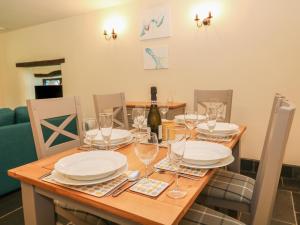 a wooden table with plates and wine glasses on it at Old Stable Cottage in Okehampton