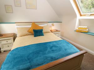 a bedroom with a bed with blue sheets and a window at Old Stable Cottage in Okehampton