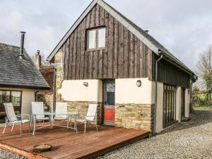 a house with a wooden deck and a table and chairs at Old Stable Cottage in Okehampton