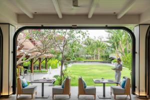 a woman standing outside of a large glass door at Melia Koh Samui in Choeng Mon Beach