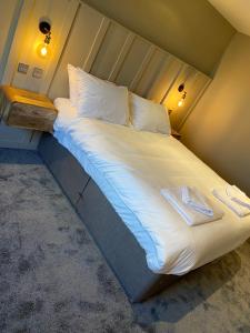 a large bed with white sheets and pillows at Lodge at Tap Haus in Mansfield Woodhouse