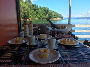 una mesa con platos de comida y vistas al agua en Casa Flutuante Ilha Grande Rj, en Praia do Bananal