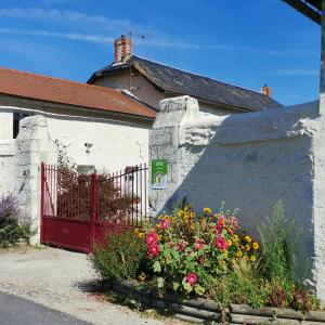 a white house with a red gate and flowers at Les gites de la Planchette in Saint-Gervais-les-Trois-Clochers