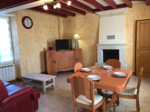 a dining room with a wooden table and a tv at Les gites de la Planchette in Saint-Gervais-les-Trois-Clochers