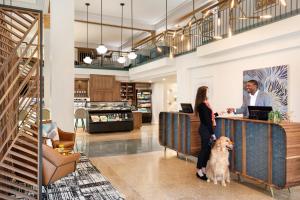 a man and a woman standing at a counter with a dog at Hotel Indigo - Winston-Salem Downtown by IHG in Winston-Salem