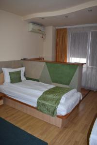 a bedroom with a large bed with a green blanket at Hotel Zimbru in Cluj-Napoca