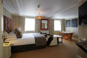 ein Schlafzimmer mit einem Bett und einer Badewanne in einem Zimmer in der Unterkunft Angel Hotel in Bury Saint Edmunds