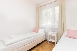 - une chambre blanche avec 2 lits et une fenêtre dans l'établissement Apartment Nevada Gdańsk Przymorze by Renters, à Gdańsk
