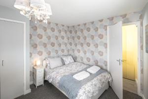 a small bedroom with a bed and a chandelier at Lighthouse of Stowmarket in Stowmarket