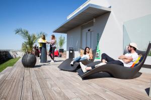 a group of people sitting in lounge chairs on a deck at Résidence Kley Toulouse in Toulouse