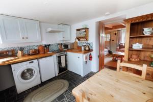 a kitchen with a washing machine and a washer at Niver Dew Holiday Cottage in Lower Boscaswell