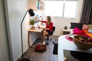 Résidence Kley Toulouse في تولوز: امرأة تجلس في مكتب في غرفة