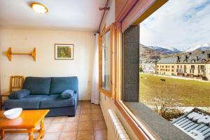 a living room with a couch and a large window at Aparthotel Trainera in Esterri d'Àneu