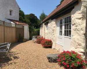 a stone house with a white door and some flowers at La Bellieuse Cottages in St. Martin Guernsey