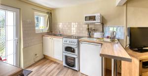 a small kitchen with a stove and a microwave at La Bellieuse Cottages in St Martin Guernsey