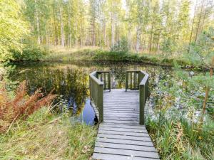 a wooden bridge over a pond in a forest at Holiday Home Käränkämökki by Interhome in Kolinkylä