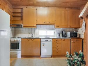 a kitchen with wooden cabinets and white appliances at Holiday Home Lomamaja 2 by Interhome in Raattama