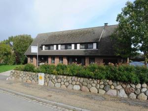 ein Backsteinhaus mit einer Steinmauer neben einer Straße in der Unterkunft La Casa Ferienwohnung Strandläufer in Steinberg