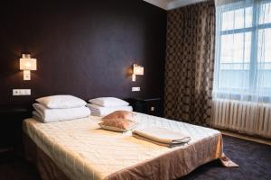 a bedroom with a bed with white sheets and pillows at Cafe Hotel Rudzons in Madona +45 photos