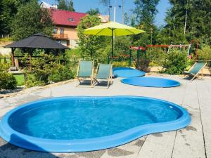 a large blue pool with two chairs and an umbrella at Pod Wodospadem Domki Całoroczne in Wisła