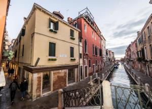 ein Kanal mit Gebäuden und Menschen, die auf einer Brücke laufen in der Unterkunft Locanda Ca' Zose in Venedig