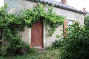 a house with a wooden door and a bunch of vines at Le Porteau Enchanteur in Sarzay