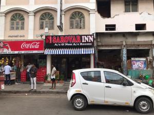 a small white car parked in front of a store at SAROVAR INN in Chennai