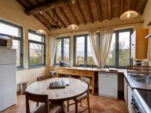een keuken met een tafel, stoelen en ramen bij Belvilla by OYO Tillia in Castiglion Fiorentino