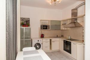 a kitchen with white cabinets and a washer and dryer at KaunasInn - AM in Kaunas