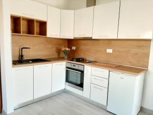 una cocina blanca con armarios blancos y fregadero en Apartment Grace Cavtat - SEA VIEW, en Cavtat